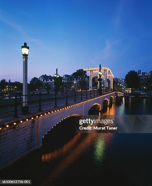 magere brug bridge (skinny bridge) on amstel river illuminated at dusk - magere brug stockfoto's en -beelden