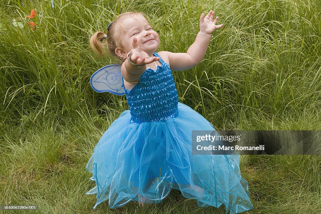 Baby girl (9-12 months) in fairy costume in grass