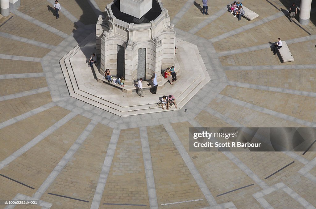 People sit in Paternoster Square in front of the London Stock Exchange in London, England.
