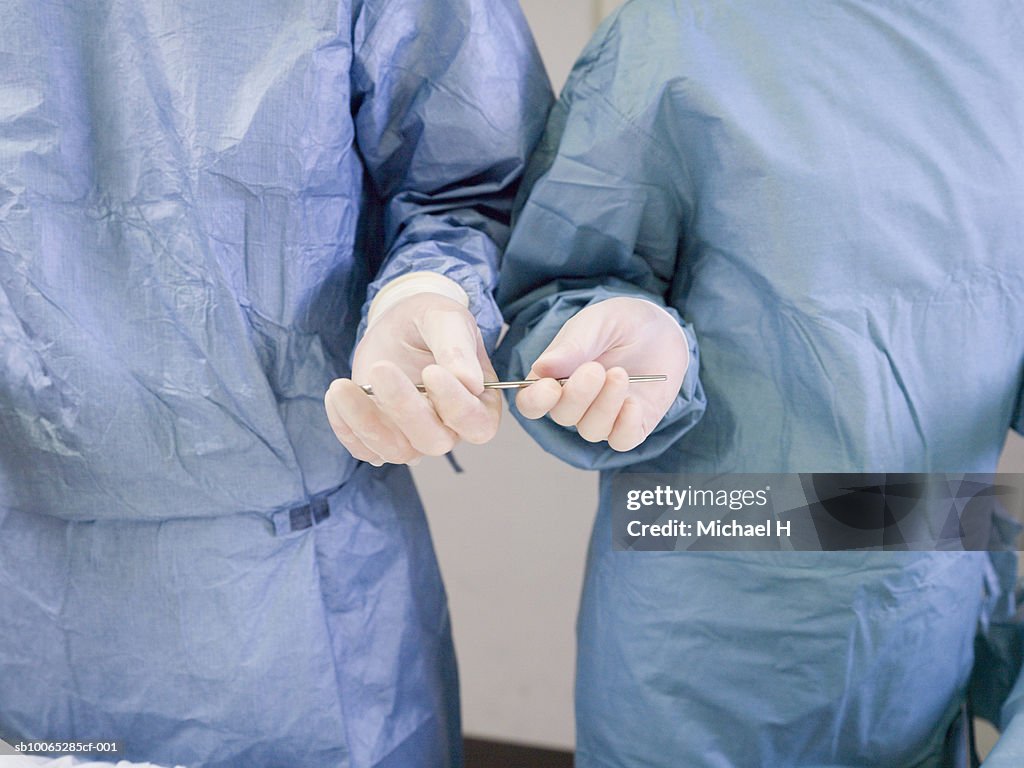 Nurse passing forceps to doctor during operation