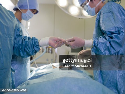 Nurse passing forceps to doctor during operation Nurse passing forceps to doctor during operation