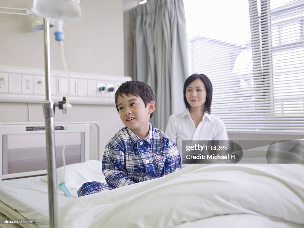 Mother beside boy (5-6) with drip in hospital bed