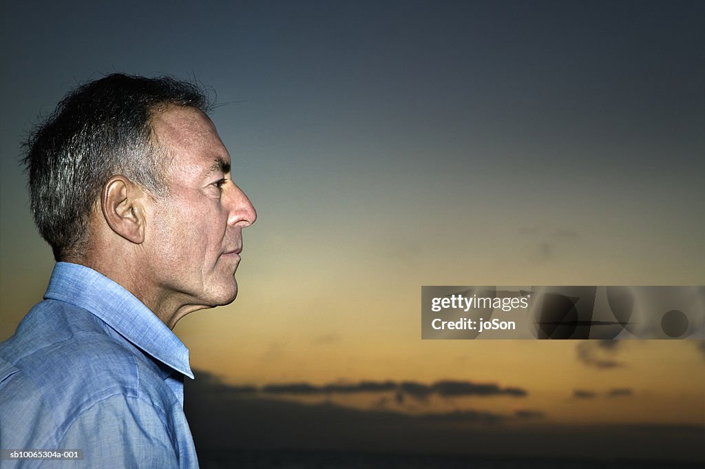 Profile of mature man, sunset in background