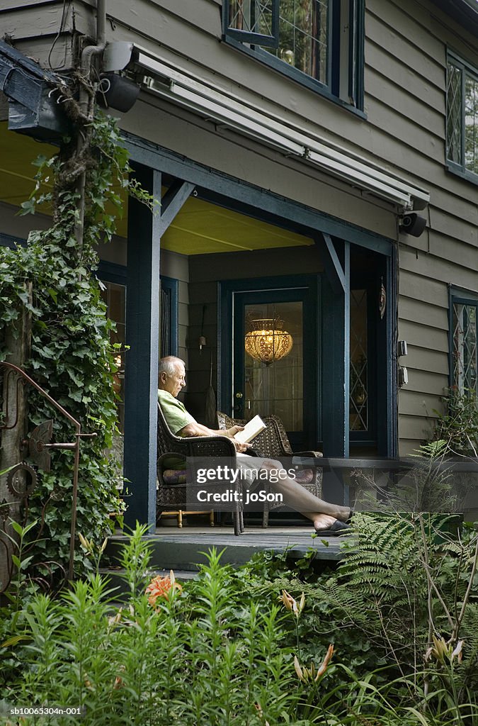 Senior man sitting on porch reading book