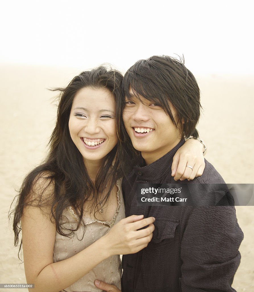 Young couple embracing and laughing outdoors, portrait