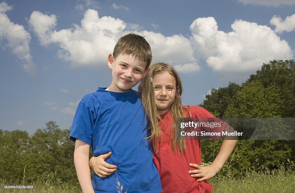 Girl and boy (8-9 years) embracing in meadow, portrait