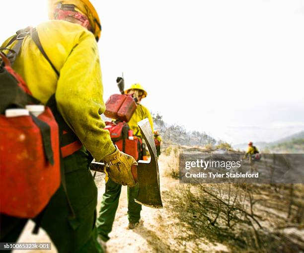 forest firefighters walking with pickaxes, rear view - wildfire firefighter stock pictures, royalty-free photos & images