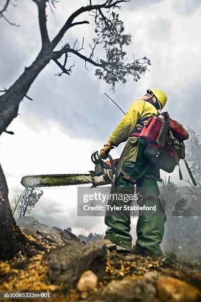 fire-fighter holding chainsaw while working - chainsaw stock-fotos und bilder