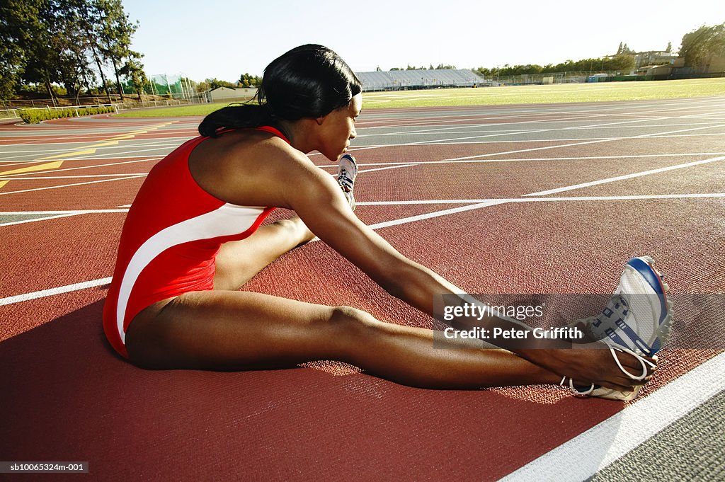 Female athlete stretching on track