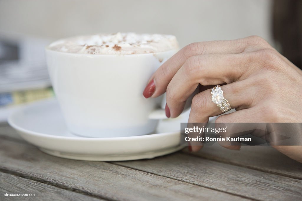 Mature woman holding cup of cappuccino, close-up