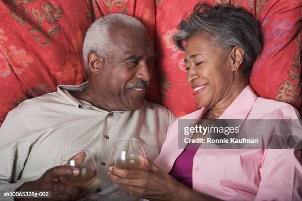 senior couple toasting champagne on bed - auf dem bauch liegen stock-fotos und bilder
