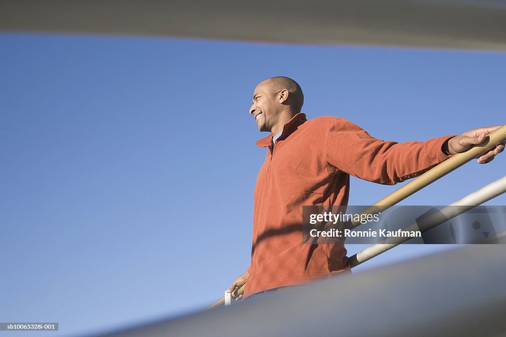 Man standing at fence, smiling, low angle view