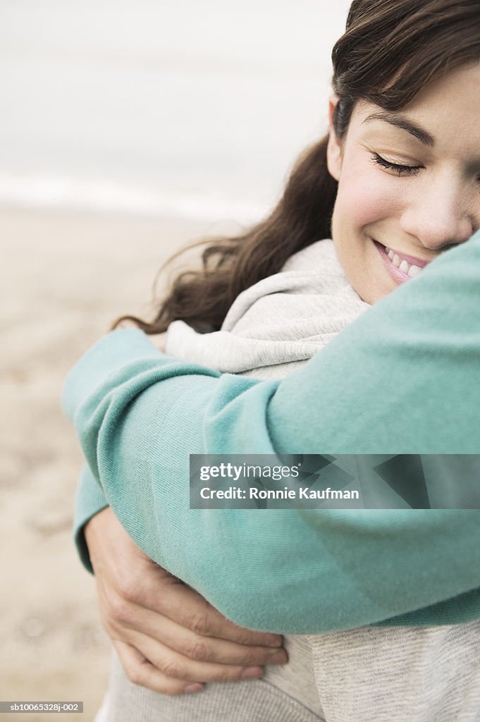 Couple embracing at beach, close-up, smiling