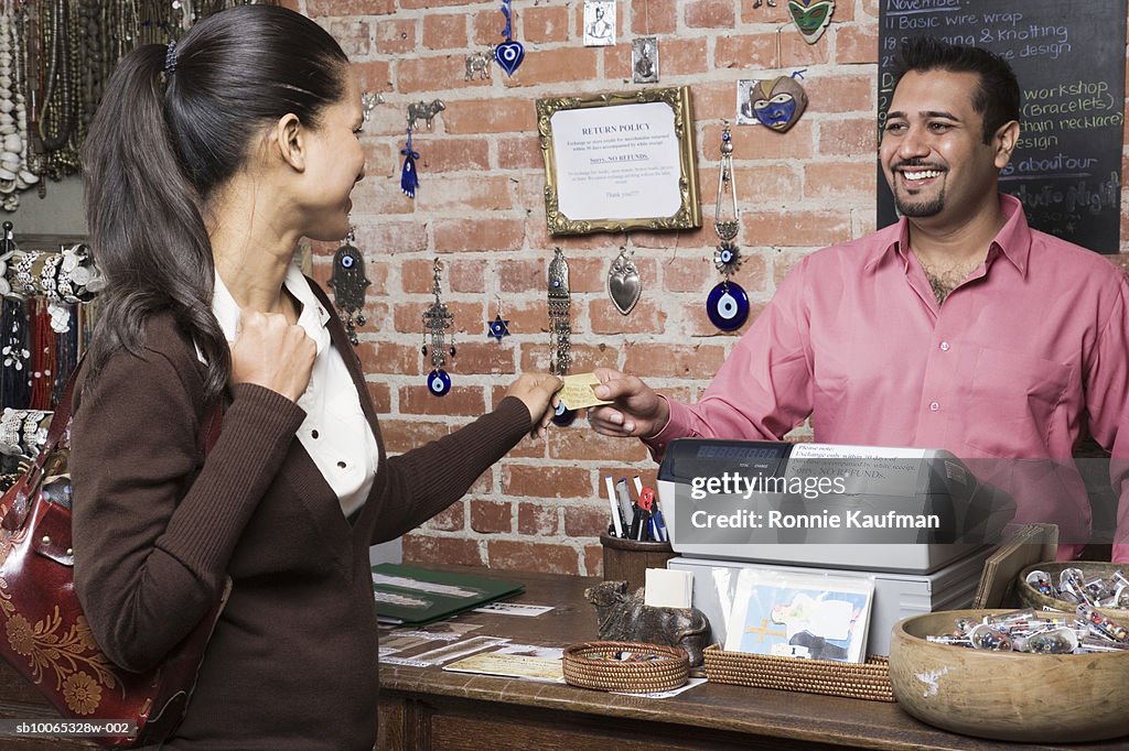 Woman paying man with credit card in shop