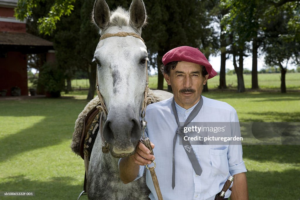 Portrait of man wearing beret holding harness of horse in park