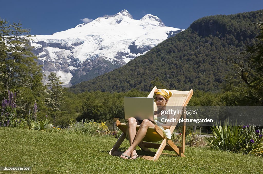 Woman sitting in deck chair, using laptop