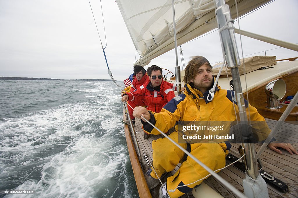 Crew sitting on side of racing yacht