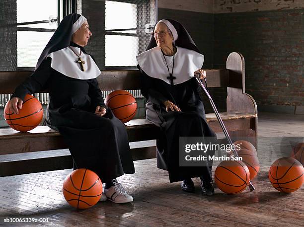 two senior nuns sitting on bench with basketballs - madre imagens e fotografias de stock