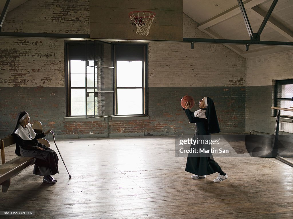 Two senior nuns in court, one throwing basket ball