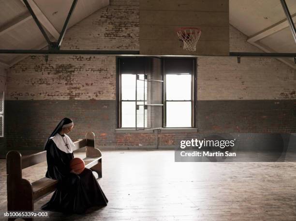 young nun sitting on bench in court holding basketball - nun habit stock pictures, royalty-free photos & images