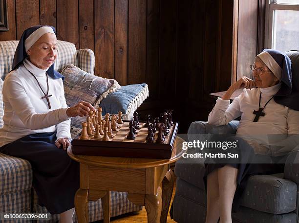 two senior nuns playing chess - nonne stock-fotos und bilder