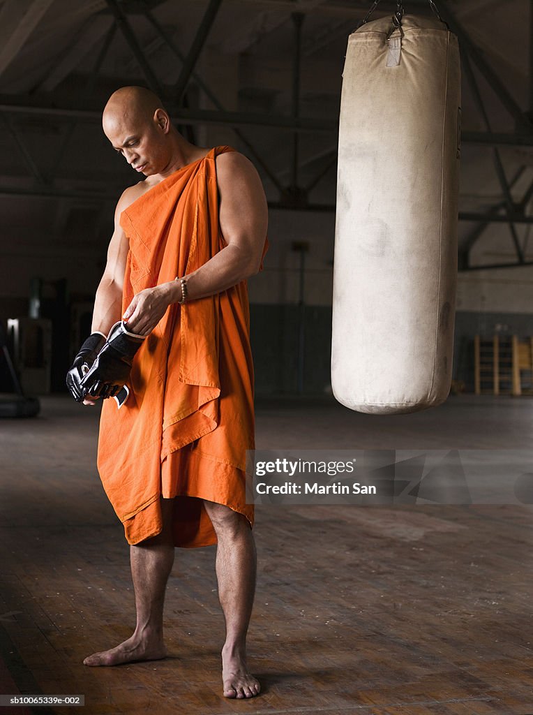 Buddhist monk wearing boxing glove in gym