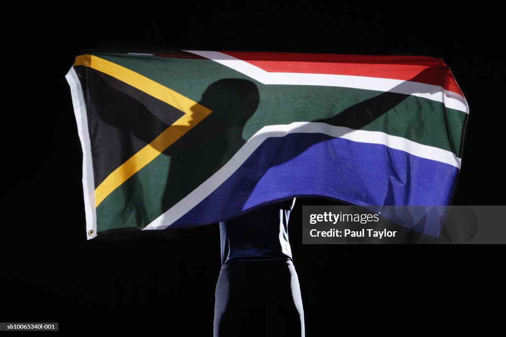 Silhouette of person holding flag of South Africa on black background