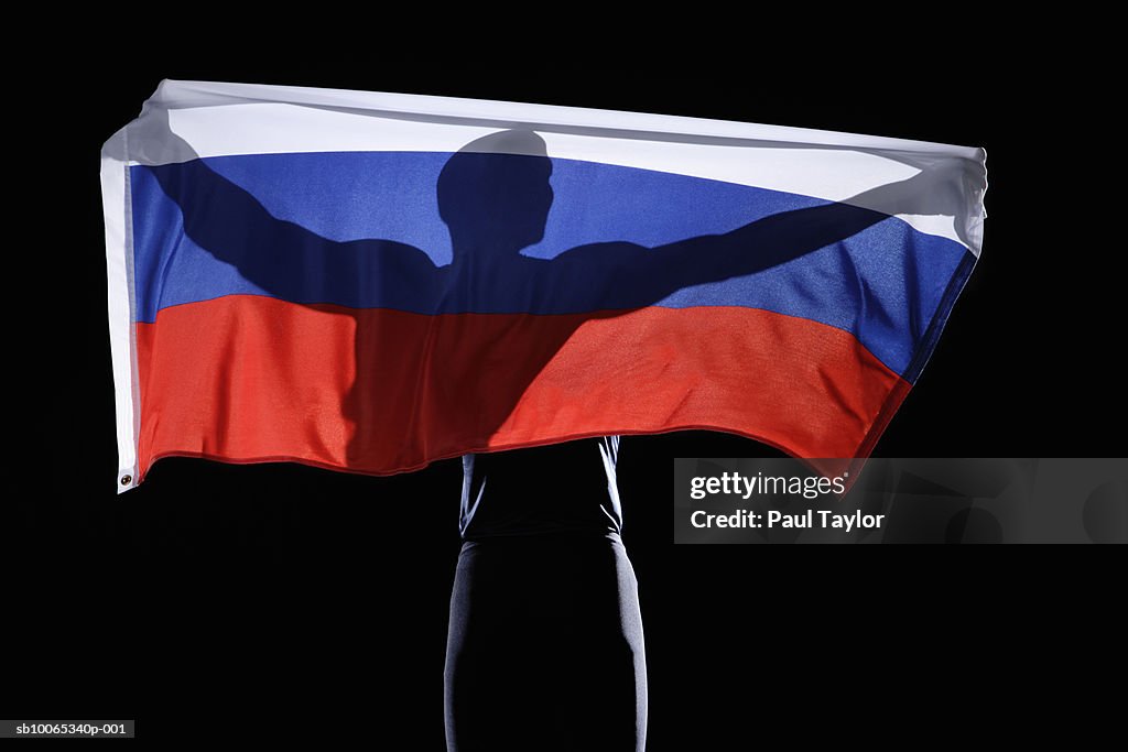 Silhouette of person holding flag of Russian Federation on black background