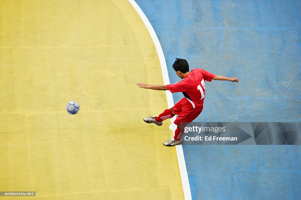 Boy kicking soccer ball, elevated view