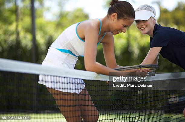 two female tennis players at net on outdoor court - red de tenis fotografías e imágenes de stock