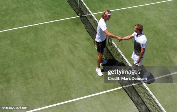 two male tennis players shaking hands over net - fairness stock-fotos und bilder