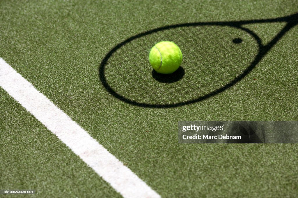 Tennis ball with racket shadow on court