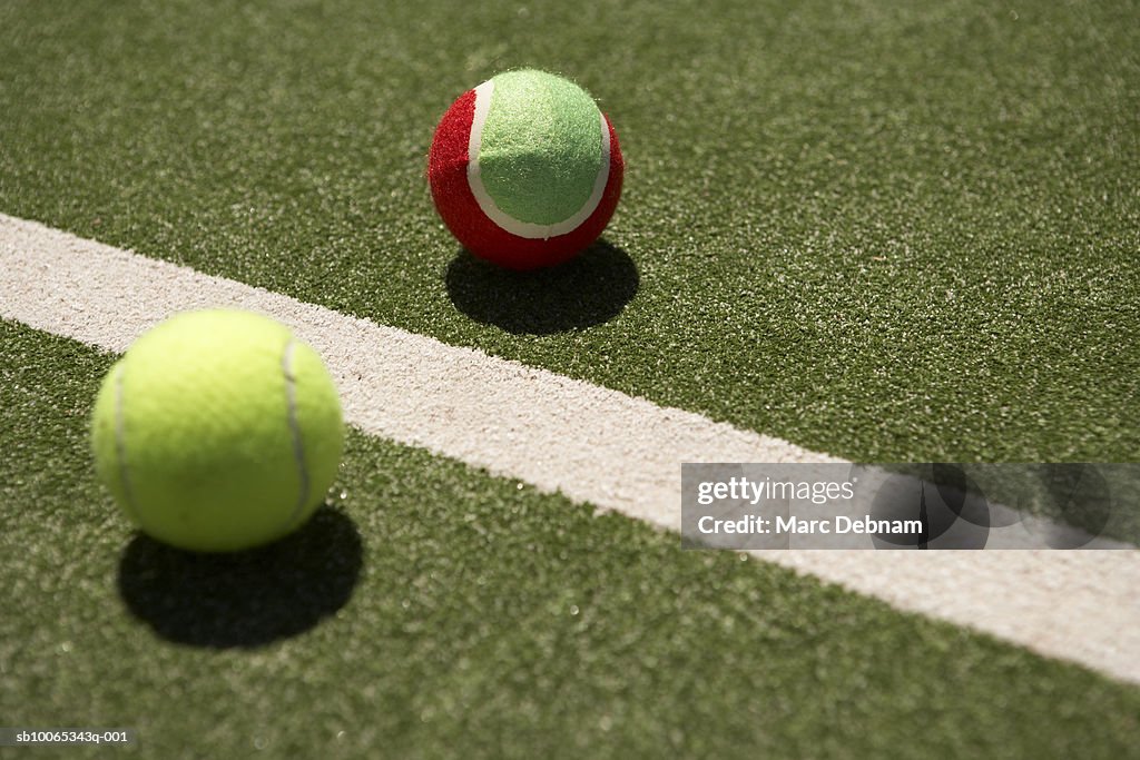 Two tennis balls beside line on court