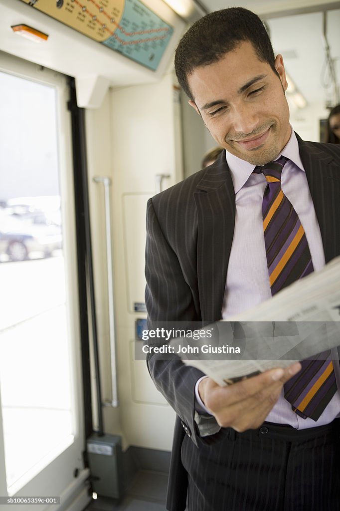 Businessman reading newspaper on tram