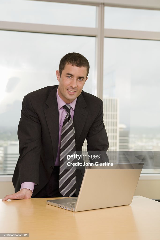 Businessman leaning on desk, portrait