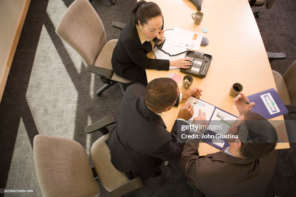 Three businesspeople discussing in conference room, elevated view