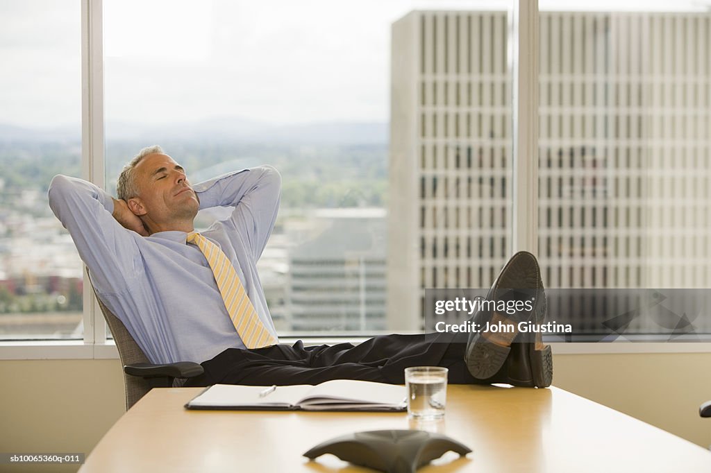 Businessman leaning on chair with hands behind head, eyes closed