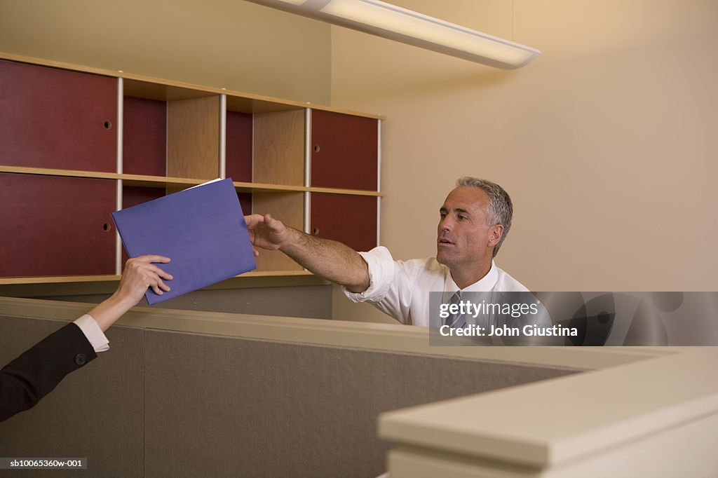 Mature man passing file to woman