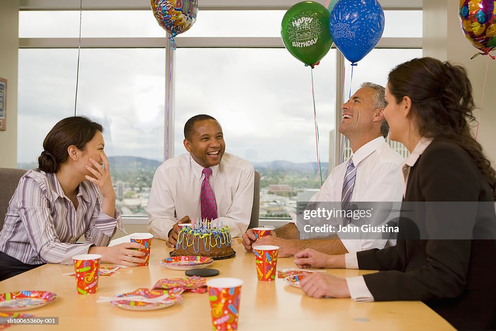Four businesspeople celebrating birthday, laughing