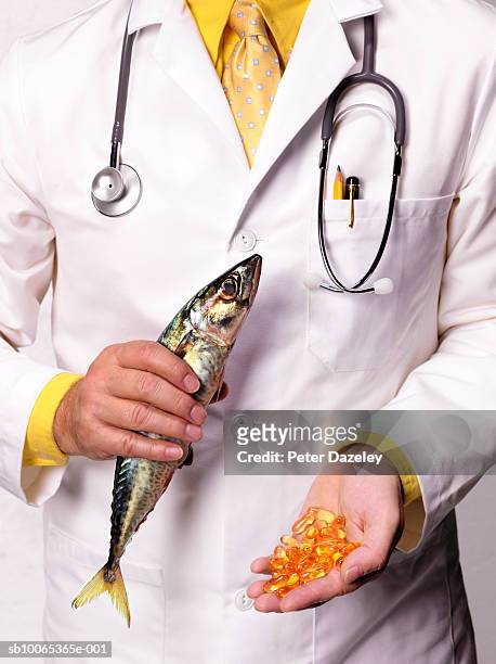 doctor holding mackerel and cod liver oil tablets, close-up, mid section - omega 3 stock-fotos und bilder