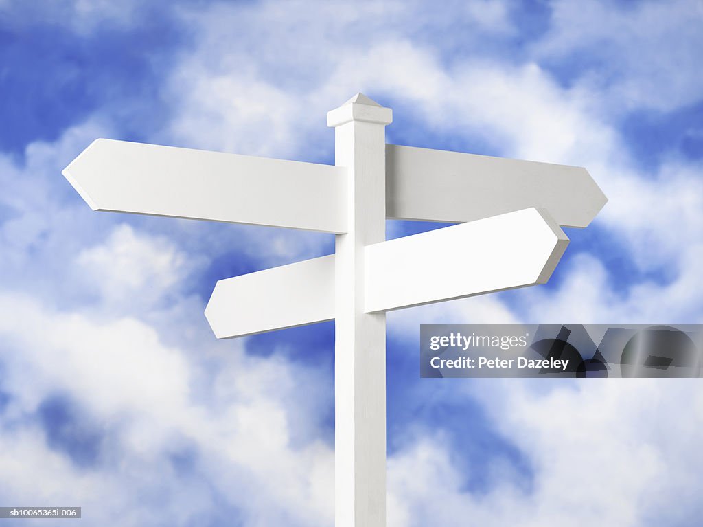 Blank sign post against cloudy sky