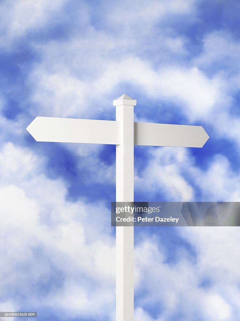 Blank sign post against cloudy sky
