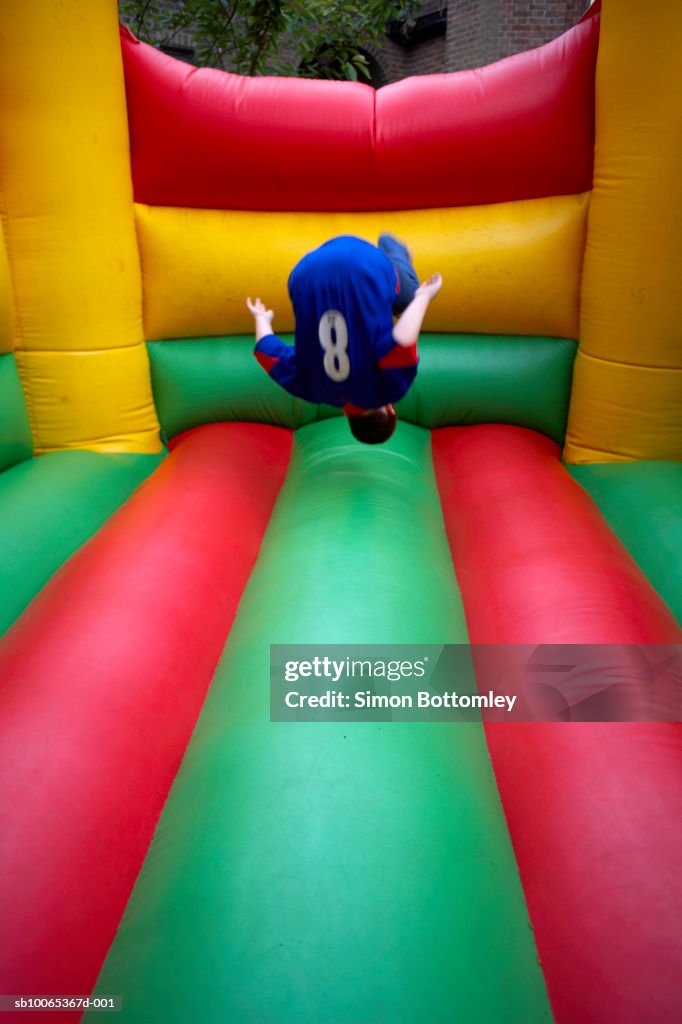 Boy (13-14) jumping in bouncy castle