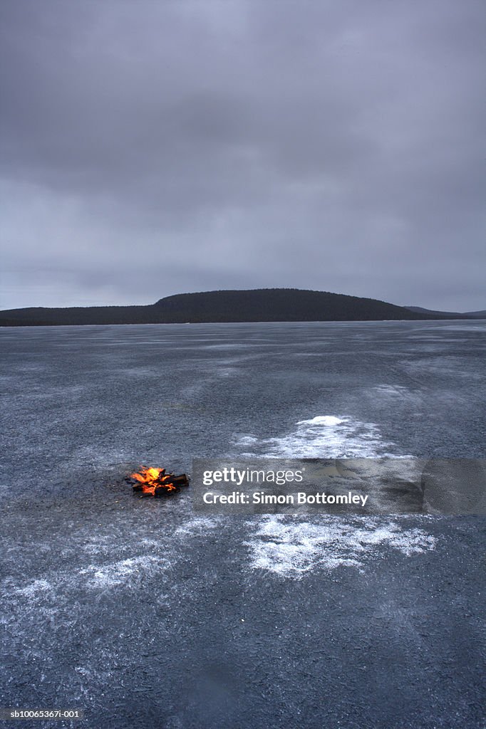 Log fire burning on frozen lake