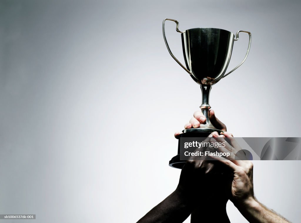 Two men holding trophy, close-up