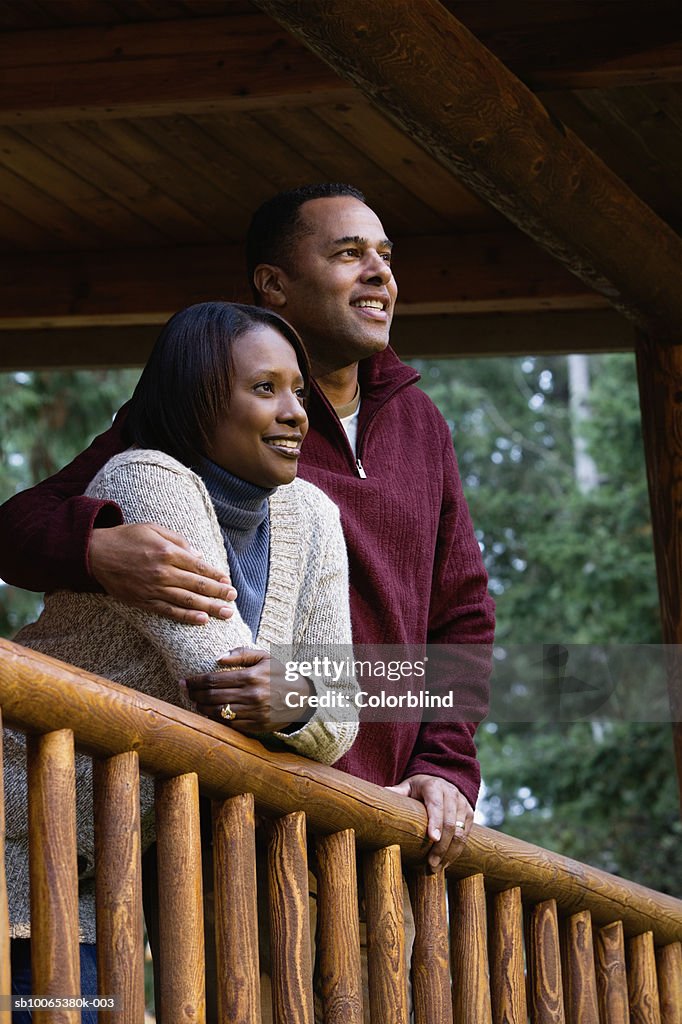 Couple on porch, looking at view, smiling