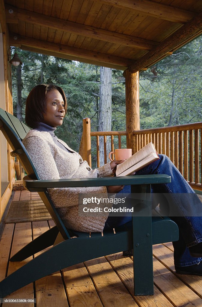 Mature woman sitting on porch, reading book