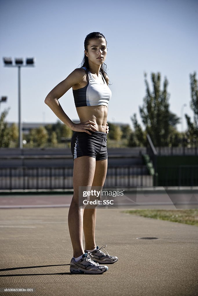Female athlete standing with hand on hip