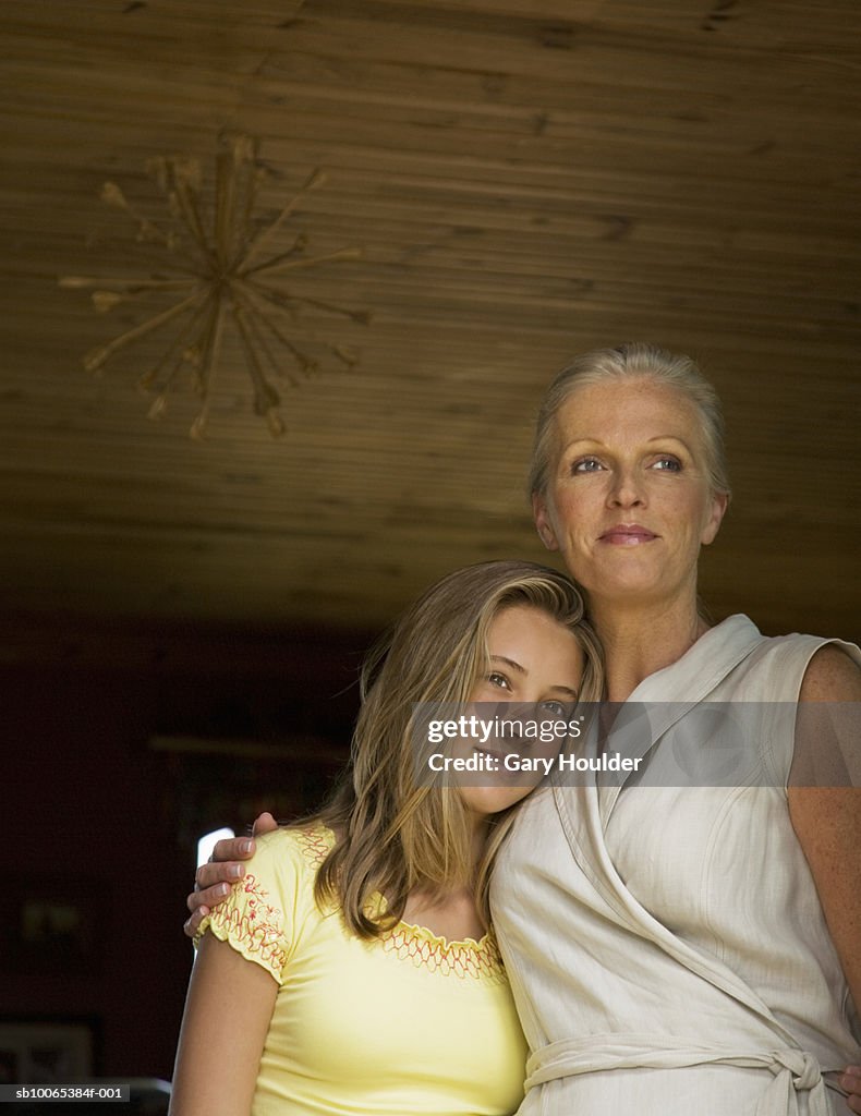 Mother and daughter (12-13) embracing, low angle view