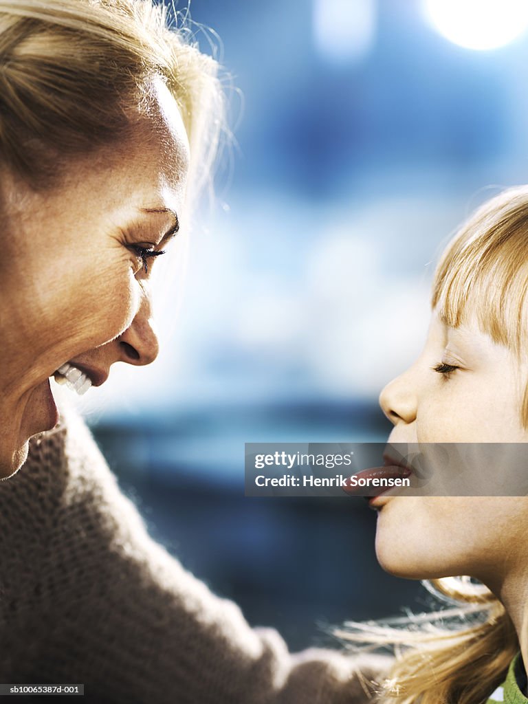 Profiles of mother and daughter (6-7), girl sticking out tongue